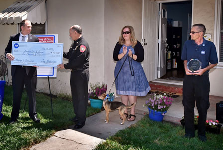 ADT vice president of marketing Jay Robertson presents a check for $10,000 to Anaheim Fire & Rescue’s Deputy Chief Rusty Coffelt as  Amber Cooper, Fiona and Dave Tompkins look on.