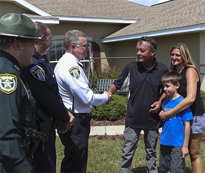 Terry France (with Colleen and Jacob) thanks Chief Reeser, Officer Tucker and Deputy Cohen outside the France home a month after the ordeal.