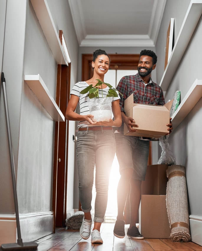 Couple moving into an a new home together and carrying boxes to unpack