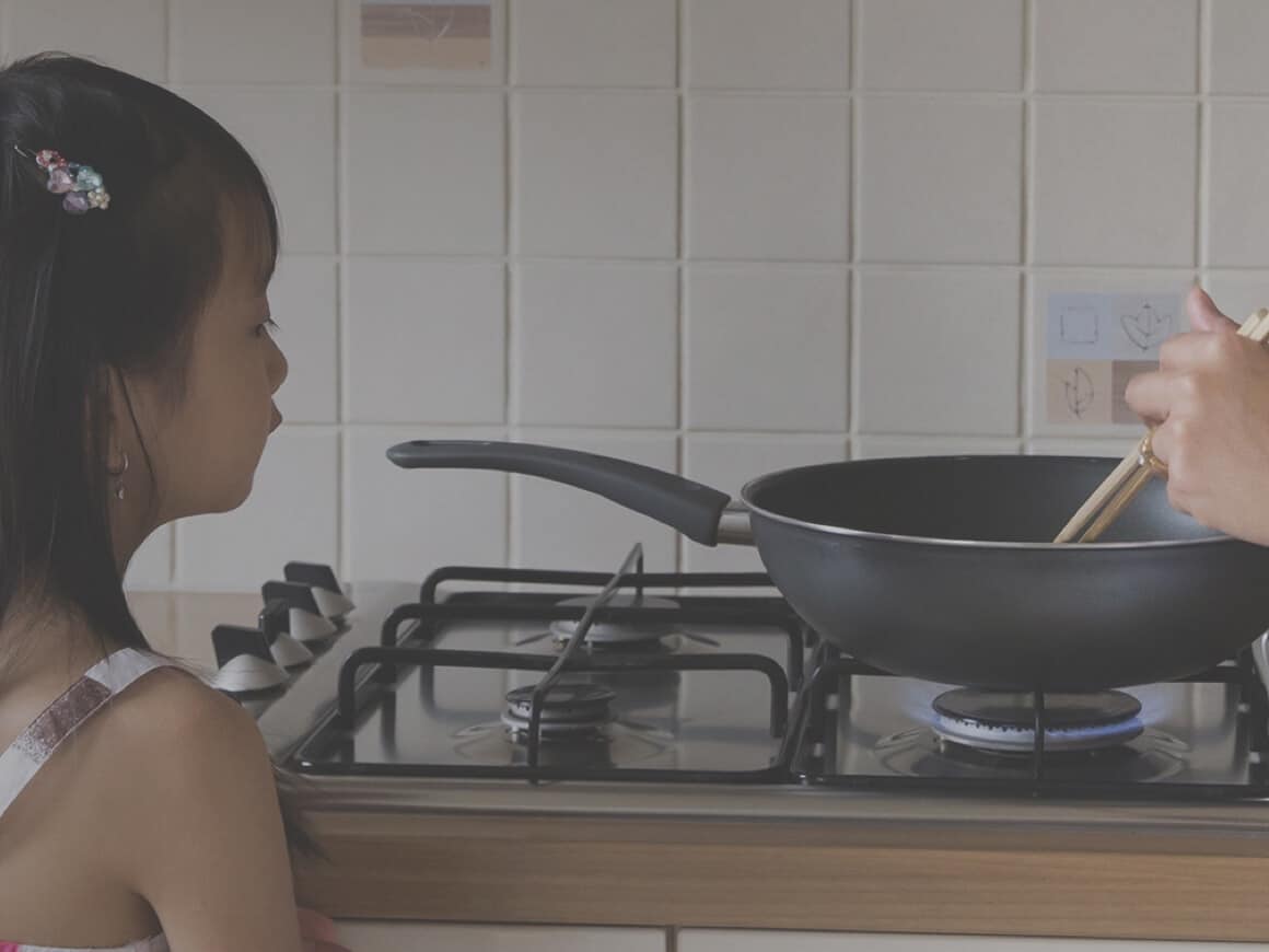 Little girl looking at pan on stove