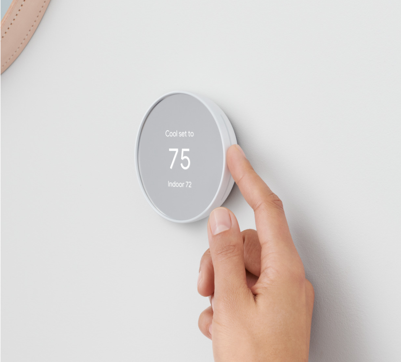 Google Nest Thermostat on a wall with a hand adjusting the temperature 