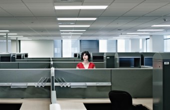 Lone woman in a cubicle among many empty office cubicles