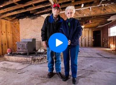 Two seniors standing in a fire-damaged room