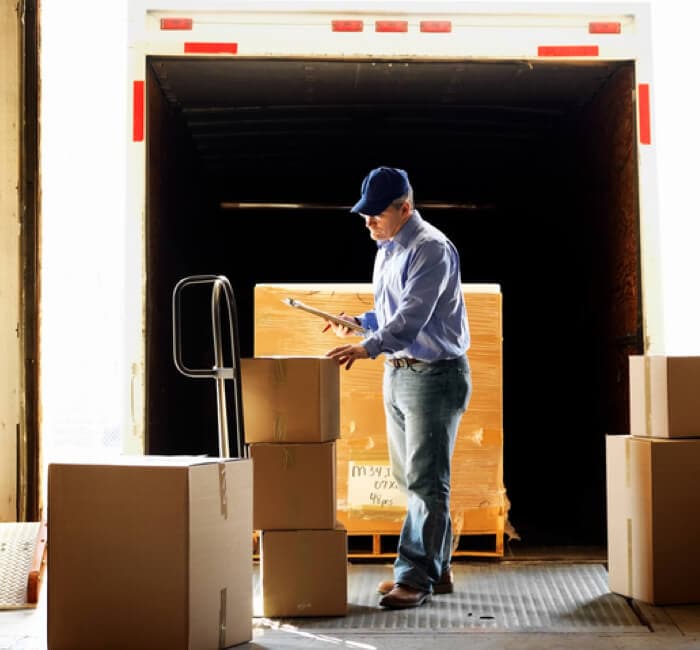 Man with clipboard looking at boxes next to a pallet Man with clipboard looking at boxes next to a pallet