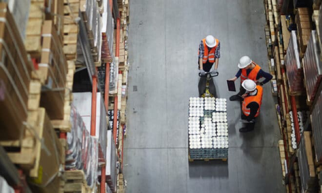 Three workers looking at a pallet in the warehouse Three workers looking at a pallet in the warehouse