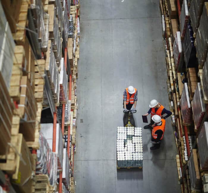 Three workers looking at a pallet in the warehouse Three workers looking at a pallet in the warehouse
