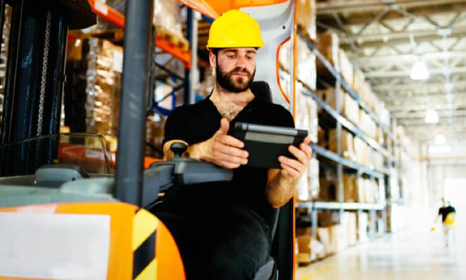 Man on a forklift looking at tablet Man on a forklift looking at tablet