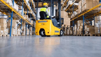 Worker driving forklift in a warehouse Worker driving forklift in a warehouse
