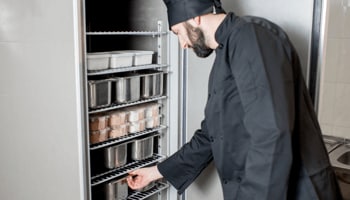 Man working in restaurant opening up freezer Man working in restaurant opening up freezer