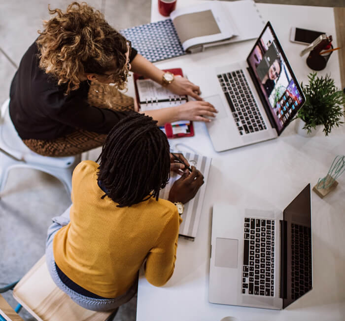 Two coworkers looking at laptop together Two coworkers looking at laptop together