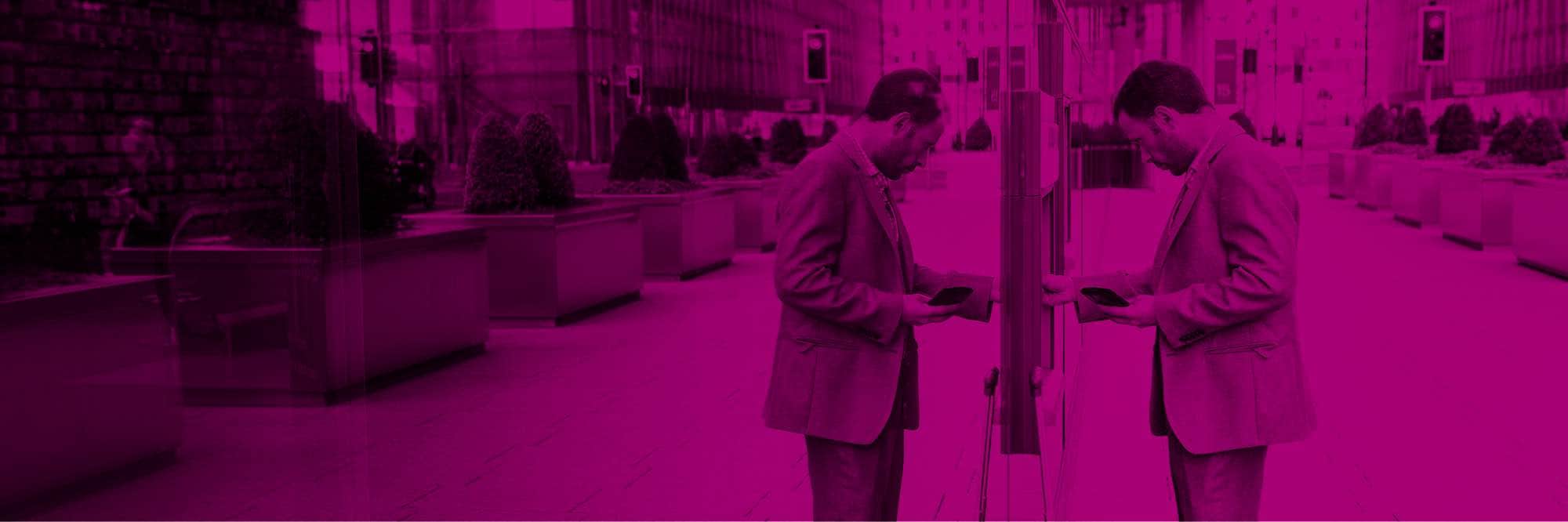 Man on city sidewalk using ATM machine