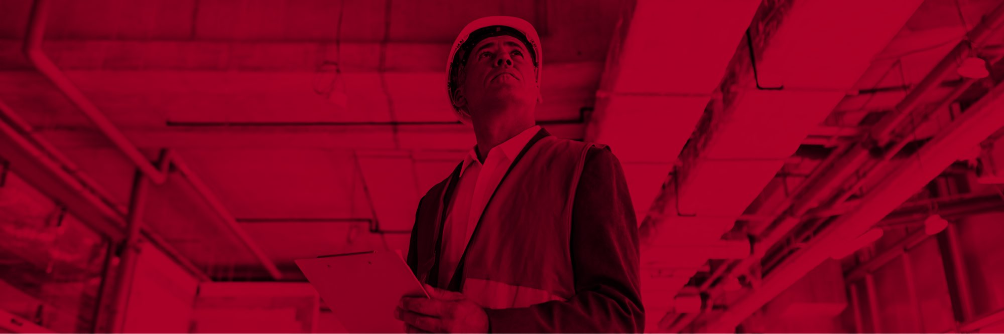 Man in hard-hat and safety vest inspecting building installations