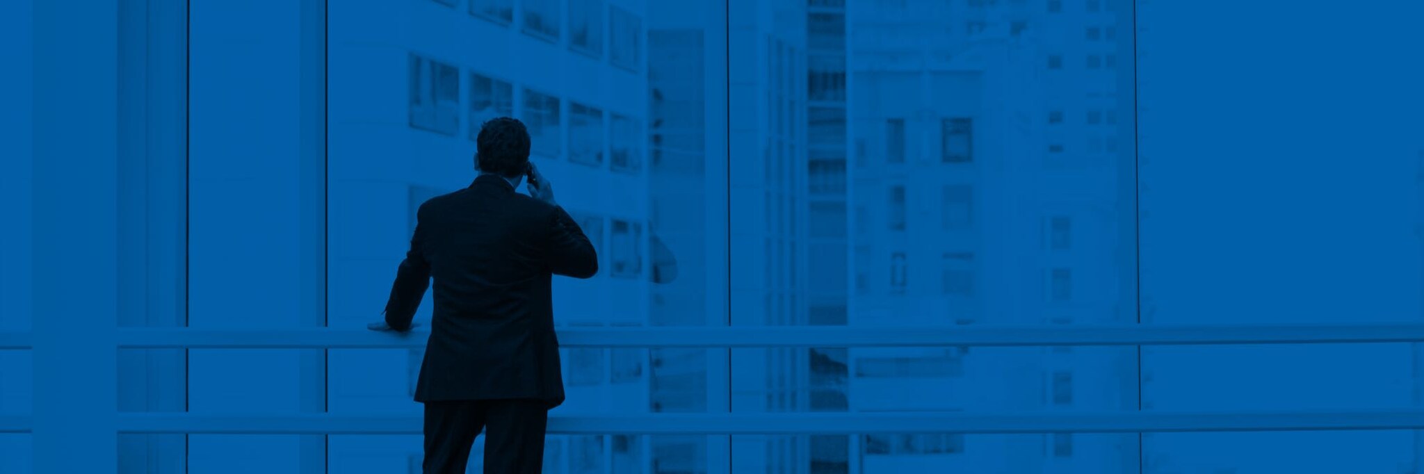 Man on phone looking out window in high-rise office building
