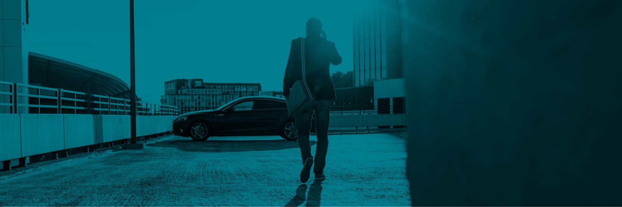 Man on phone walking toward car on top deck of parking structure