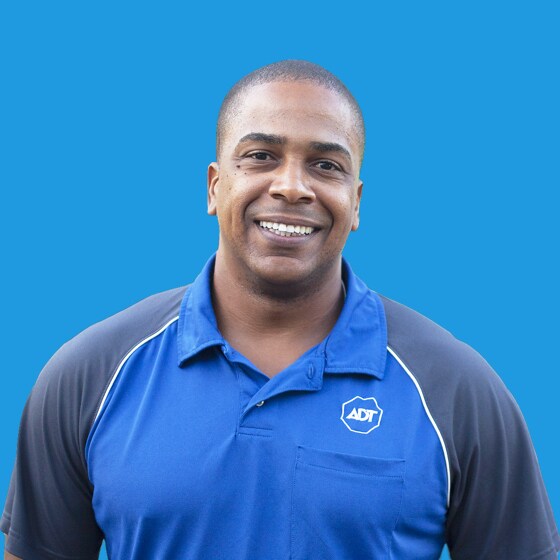 Man wearing an ADT polo and smiling against a blue background