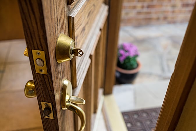 Brown front door open with a key in the front lock.