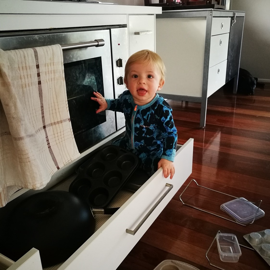 Baby boy sitting in drawer beneath stove in kitchen Baby boy sitting in drawer beneath stove in kitchen
