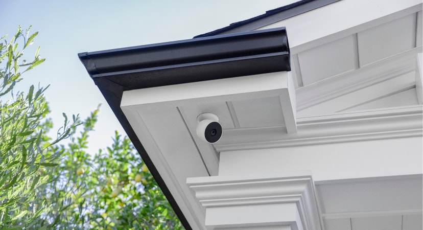 Outdoor wireless security camera mounted under the eaves of a house, providing discreet surveillance for entryways and perimeter protection.
