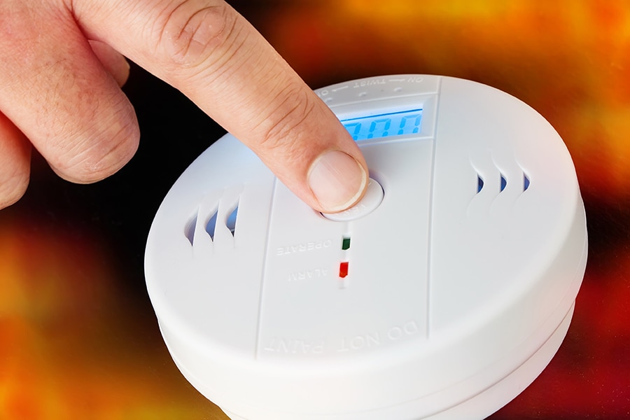 Close up of a finger testing a carbon monoxide detector.