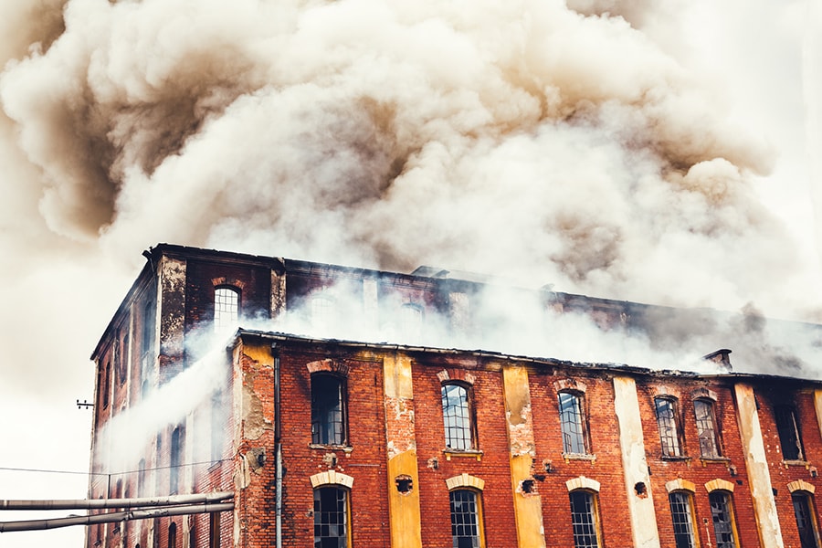 Gray clouds of smoke swirling out of an old red-brick building.