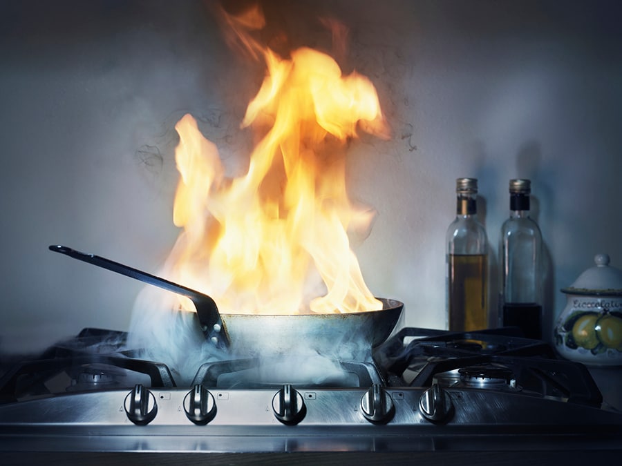 Burning grease fire in a frying pan on the stove.