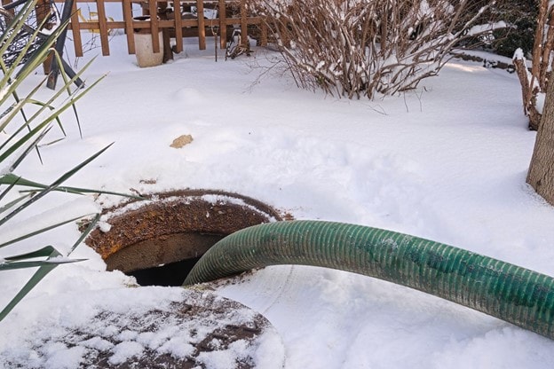 Hose going into a septic tank on a snowy day
