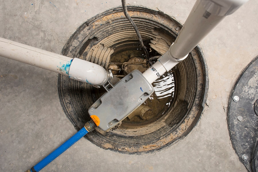 A sump pump in a basement of a home with a water-powered backup system. A sump pump in a basement of a home with a water-powered backup system.