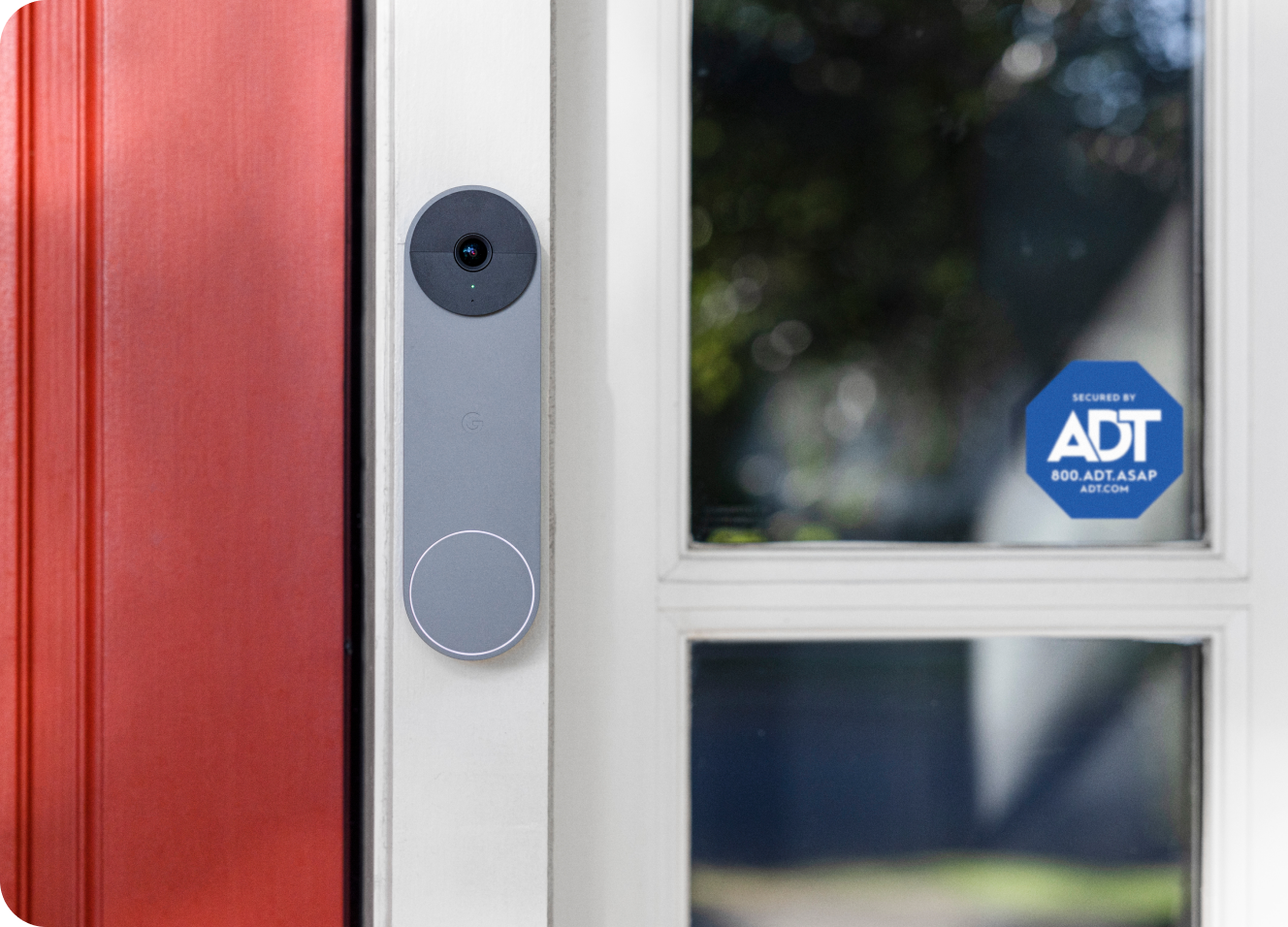 Grey Google Nest Doorbell on a frame next to an ADT window sticker