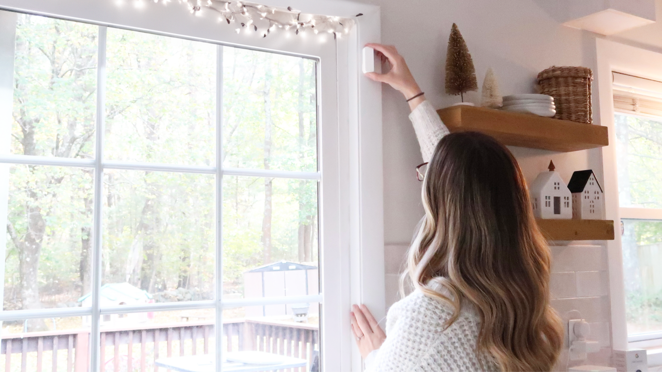 Woman self installing a window sensor in her home Woman self installing a window sensor in her home