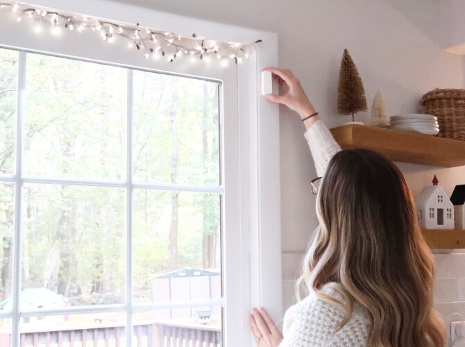 Woman self installing a window sensor in her home Woman self installing a window sensor in her home