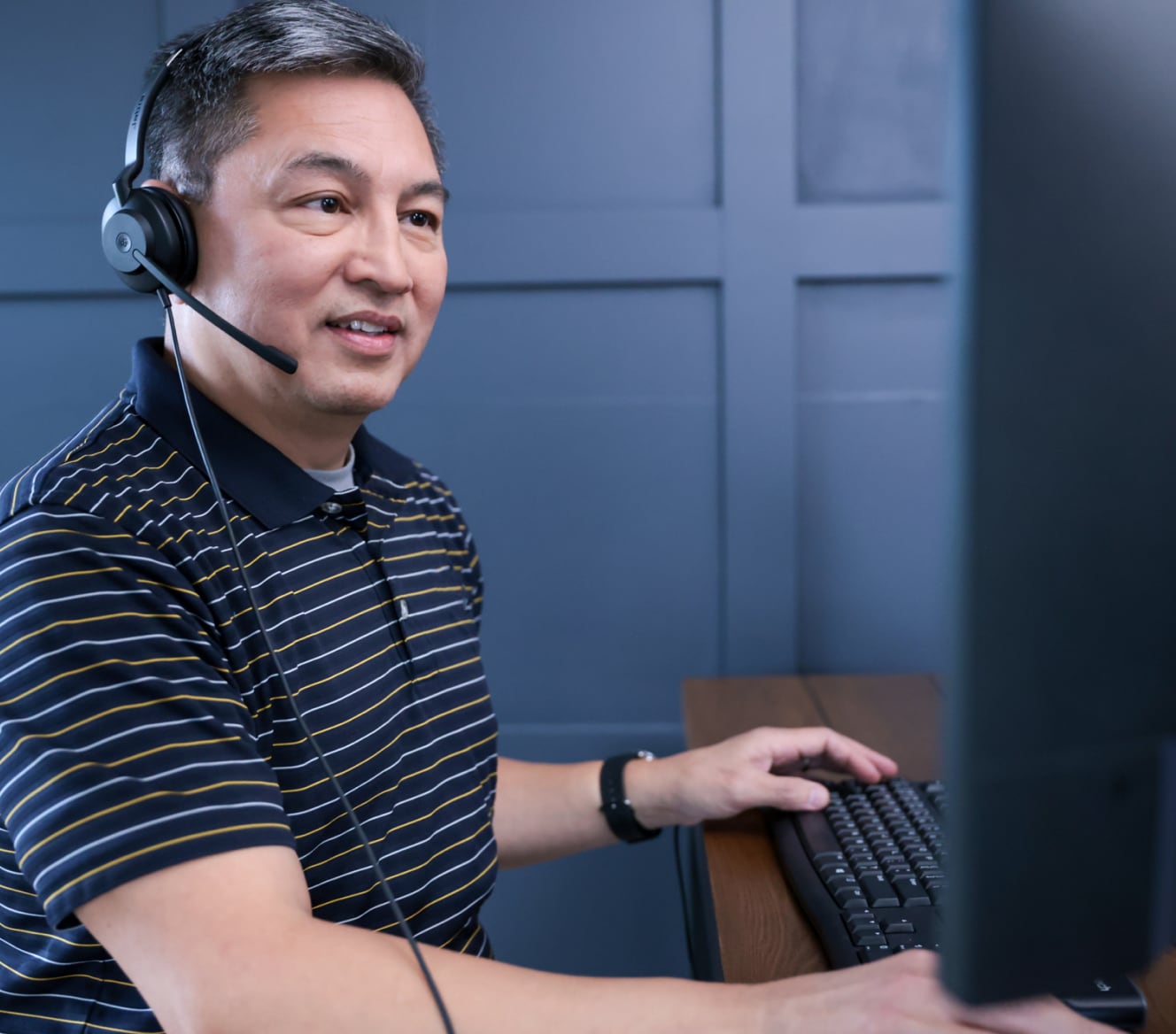 ADT customer service rep typing on his computer and troubleshooting with a customer on his headset 