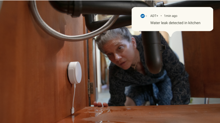 Homeowner checking her water sensor under the sink after receiving an ADT notification about water leakage