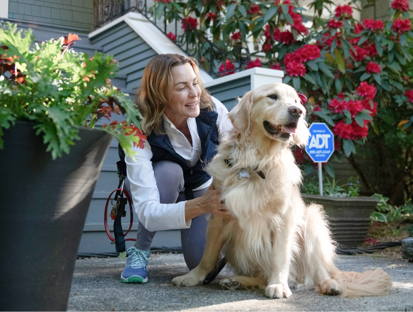 Woman kneeling next to her dog by an ADT sign