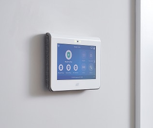 An ADT security touchscreen panel mounted on a wall, displaying system status and smart controls for business security.