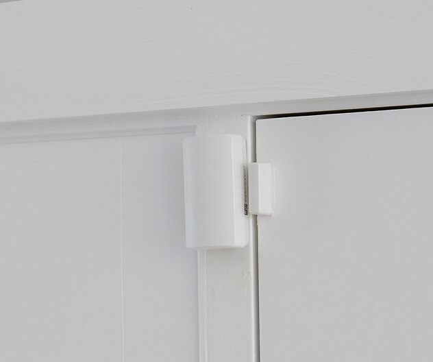A close-up of a door sensor installed on a business’s interior door, as part of a security system.