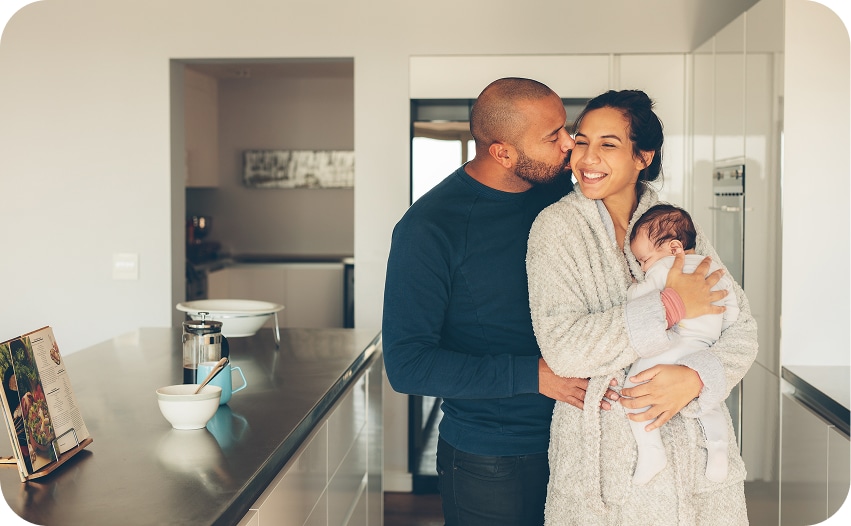 Family standing together in a kitchen with a newborn baby, representing home security solutions for different household needs.