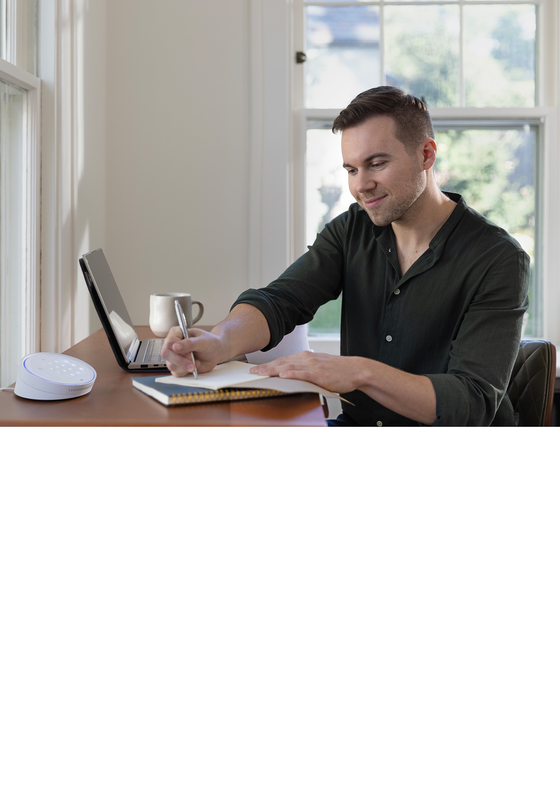 Man standing in a bright, modern entryway pressing a home security system keypad on a console table.