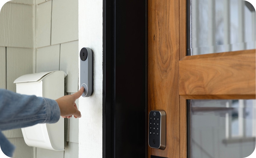 Close-up of a person unlocking a smart lock by pressing a button on a wall-mounted access device next to a front door.