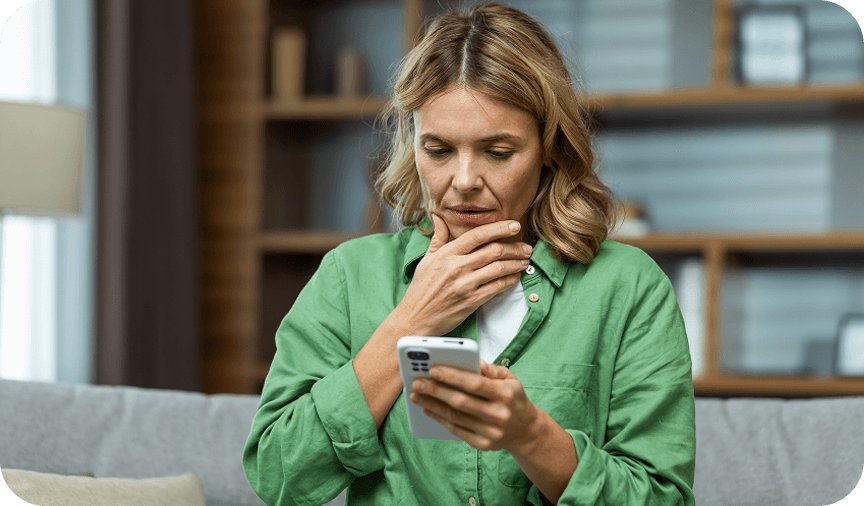 Woman in green shirt looking concerned while using her smartphone.