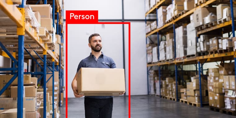 Man in a warehouse carrying a box on video surveillance 