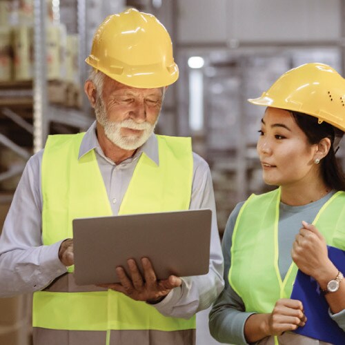 Technicians in hard hats looking at laptop