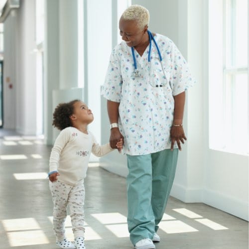 Doctor walking while holding hand of child patient