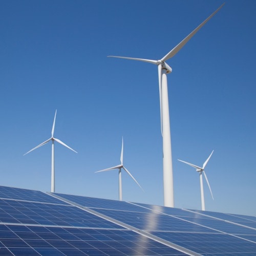 Four wind turbines rising above solar panel array