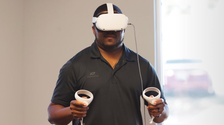 Operator wearing Virtual Reality headset and holding controllers for robot operation