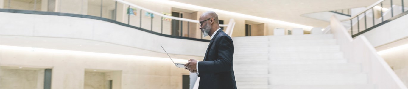 Man crossing atrium with open laptop