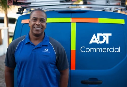 Smiling ADT Commercial technician at rear doors of ADT Commercial van
