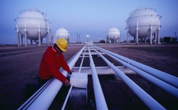 Worker examining power junction at liquid natural gas storage facility