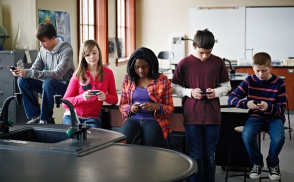 Five students looking down at their phones
