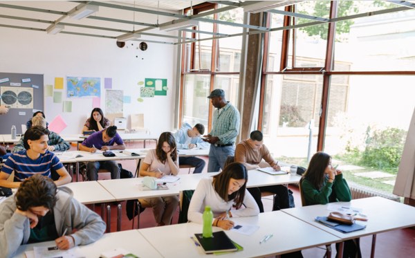 Teacher walking down row of classroom as students work