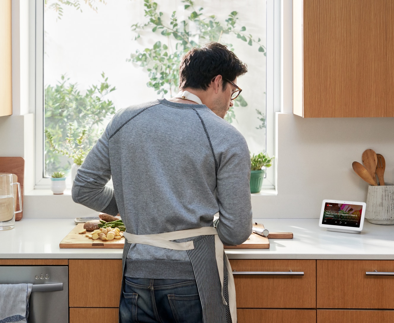 Man booking in the kitchen while looking at a recipe on the Google Nest Hub 2nd Gen